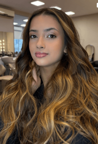 Morena iluminada com mechas caramelo e ondas